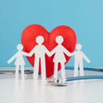 Figure di carta di famiglia che si tiene per mano con dietro cuore e stetoscopio