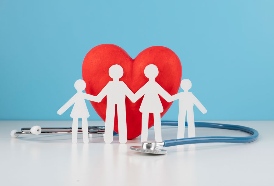 Figure di carta di famiglia che si tiene per mano con dietro cuore e stetoscopio